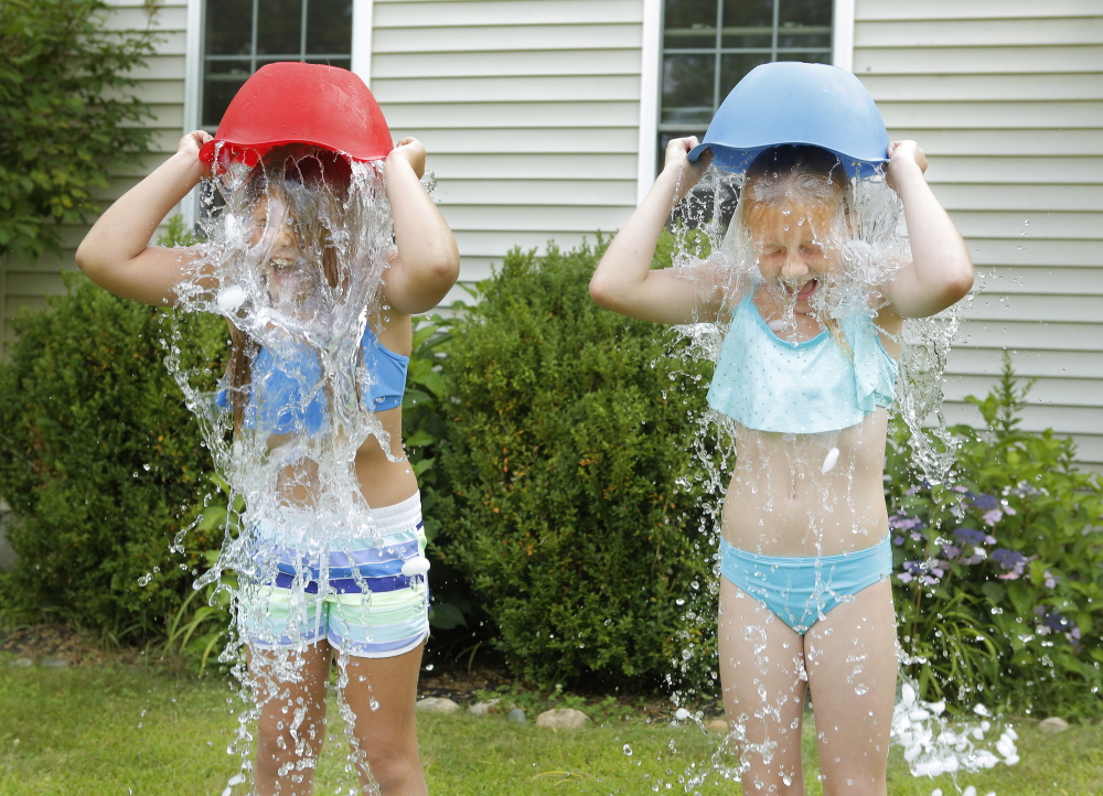 Matilda Bordas, left, and Rowan Pow, both 9, dump buckets of ice and water on their heads Tuesday in Bordas’s front yard in Kennebunk. The were nominated by a friend in the ALS Ice Bucket Challenge, which is using social media to raise money to fight amyotrophic lateral sclerosis, or Lou Gehrig’s disease.