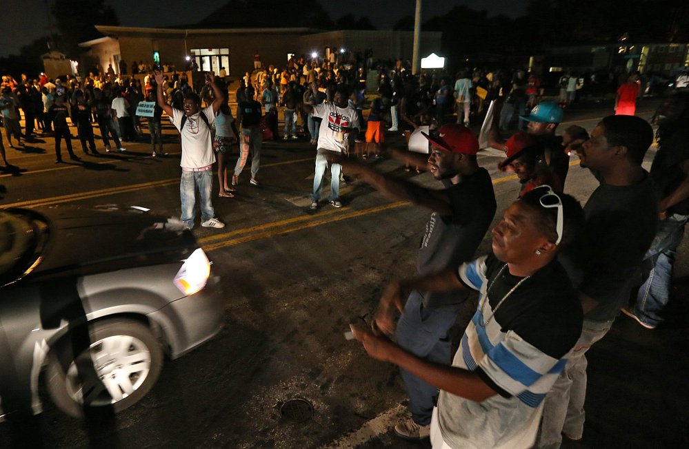 A group demonstrates along and in the middle of Chambers Rd. outside the Greater St. Mark Missionary Baptist Church after the conclusion of a gathering with Michael Brown’s family and Rev.