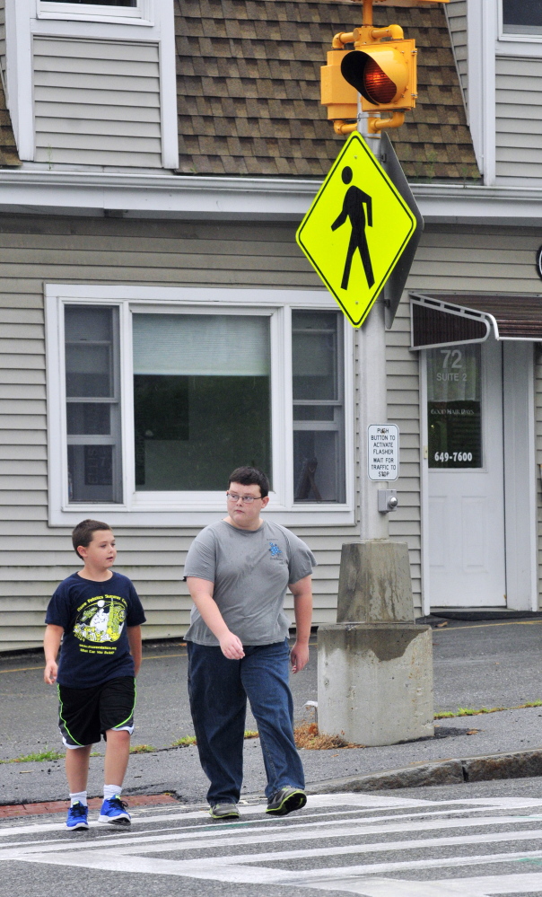 Keygan Wyman, 10, left, and his brother Ayden Wyman, 11, cross Western Avenue on Wednesday in the crosswalk where it intersects with Florence and Cushman streets. When school starts later this month, there won’t be a crossing guard there like there’s been in previous years.