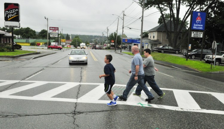 Jason Wyman, center, and his sons Keygan, 10, left, and Ayden, 11, cross Western Avenue on Wednesday in the crosswalk where it intersects with Florence and Cushman streets. When school starts later this month, there won’t be a crossing guard there like there’s been in previous years.