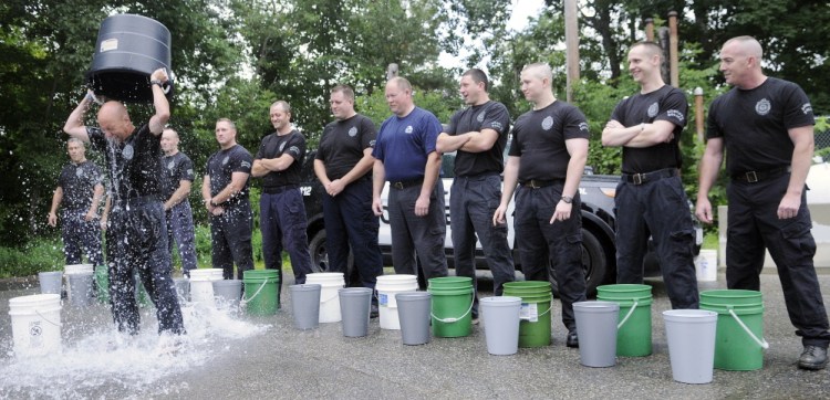 Augusta Police Sgt. Christian Behr pours a bucket of ice water over his head in the agency’s parking lot as part of a challenge to raise money for ALS research. Several officers took the ice bucket challenge.