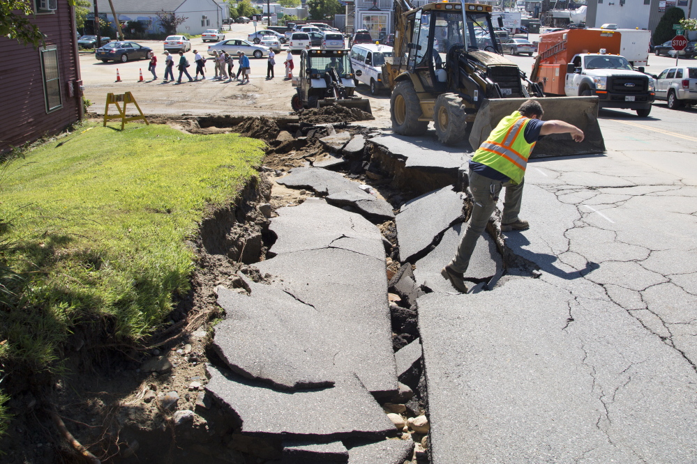 PORTLAND, ME - AUGUST 14: Utility workers surveyed and dug out a hole in front of Rufus Deering Lumber on Commercial St. the day after heavy rains and flash flooding on Thursday, August 14, 2014. (Photo by Yoon S. Byun/Staff Photographer)