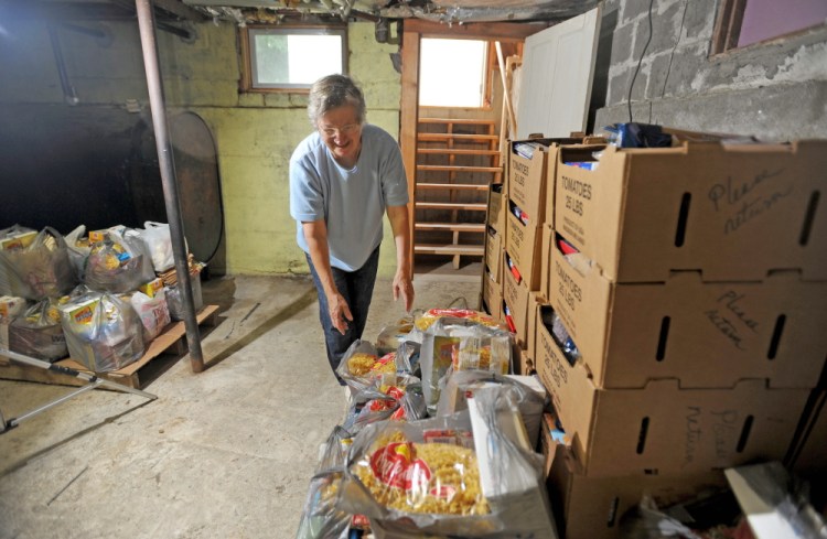 Louise Carl, food pantry coordinator at the Bingham Area Food Pantry, organizes the last pallet of donated food in the Bingham Area Food Pantry in the basement of St. Peter Church rectory in Bingham on Thursday. The pantry is shutting down after 33 years because the building is being sold.