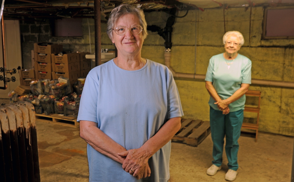 Louise Carl, foreground, food pantry coordinator at the Bingham Area Food Pantry, and long-time volunteer Rita Seguin, background, stand amid the dwindling supplies of food in the Bingham Area Food Pantry in the basement of the St. Peter Church rectory in Bingham on Thursday. The pantry is shutting down after 33 years because the building is being sold.