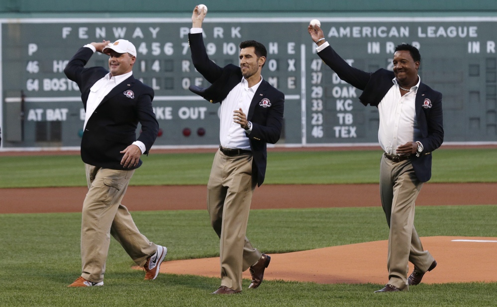 Boston Red Sox greats Roger Clemens, Nomar Garciaparra and Pedro Martinez, from left, throw out the ceremonial first pitch prior to Thursday’s game at Fenway Park in Boston. Clemens, Garciaparra and Martinez were inducted into the Boston Red Sox Hall of Fame earlier in the day.