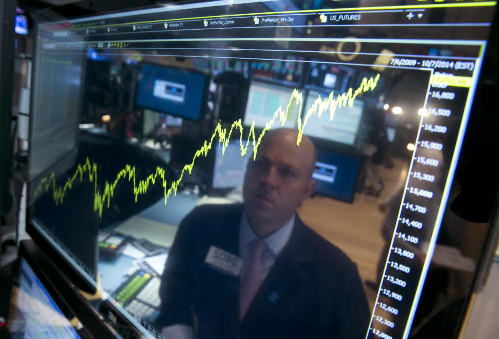 In this July 3, 2014 file photo, specialist Jay Woods is reflected in a screen at his post that shows five years of the Dow Jones industrial average, on the floor of the New York Stock Exchange.