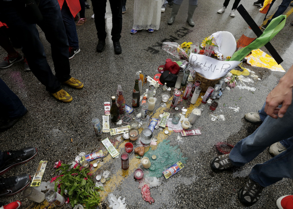 People gather around a makeshift memorial for Michael Brown on Saturday, located at the site where Brown was shot by police a week ago in Ferguson, Mo.