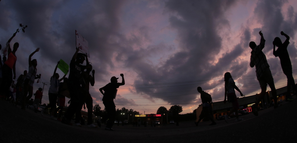 In this photo taken with a fisheye lens, people protest Monday, Aug. 18, 2014, for Michael Brown, who was killed by police Aug. 9 in Ferguson, Mo. Brown's shooting has sparked more than a week of protests, riots and looting in the St. Louis suburb. (AP Photo/Charlie Riedel)