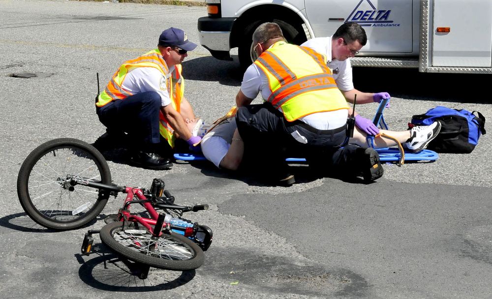 Rescue personnel treat an injured bicyclist after a collision with a vehicle on College Avenue in Waterville.
