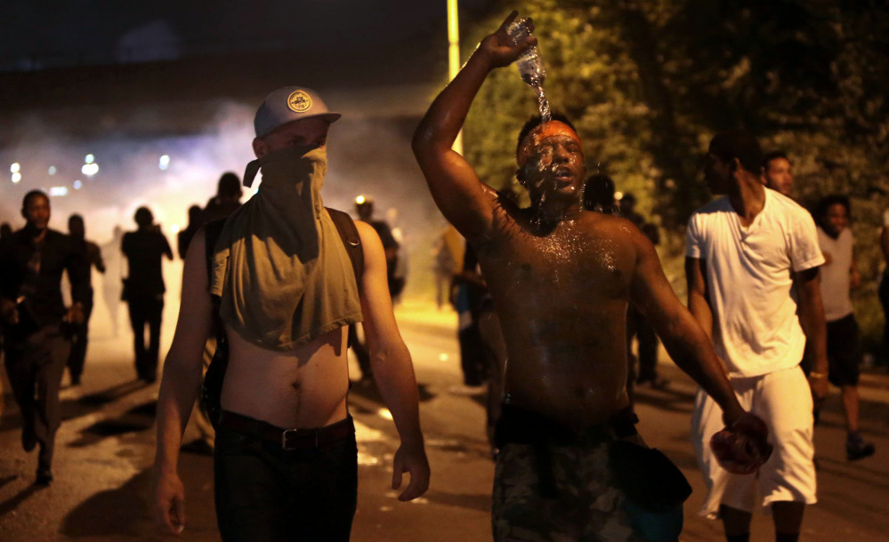 Protestors retreat from tear gas after marching toward police in Ferguson, Mo., Sunday.