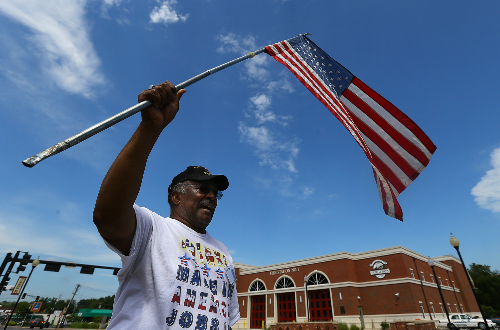 Walter Rice, 75, a life-long Ferguson resident and a Vietnam veteran, waves an American flag as he protests Tuesday in front of the Ferguson police department.
