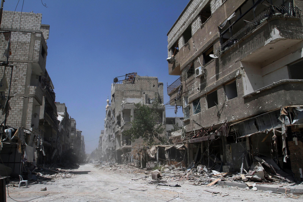 In this photo taken during a Syrian government-led media tour, buildings damaged during battles between Syrian troops and rebels stand along an empty street in Mleiha, some 10 kilometers (6 miles) southeast of downtown Damascus, Syria, Friday.