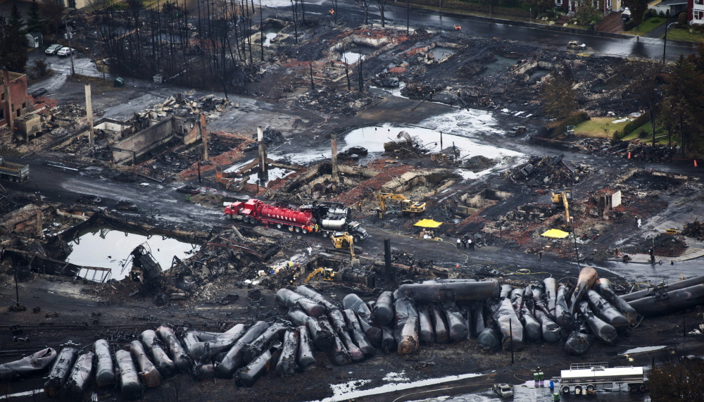 FILE - In this July 9, 2013, file photo, workers comb through debris after an oil train derailed and exploded in the town of Lac-Megantic, Quebec, killing 47 people. In response to Lac-Megantic, the National Transportation Safety Board and Transportation Safety Board of Canada in January 2014, called on regulators to require railroads to take stock of the risks along certain oil train routes and change them if needed. (AP Photo/The Canadian Press, Paul Chiasson, File)