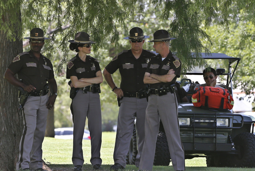 Oklahoma Highway Patrol officers watch from a distance under the shade of some trees during a rally at the state Capitol in Oklahoma City on Thursday. The rally was in response to the shooting death of 18-year-old Michael Brown in Ferguson, Mo.