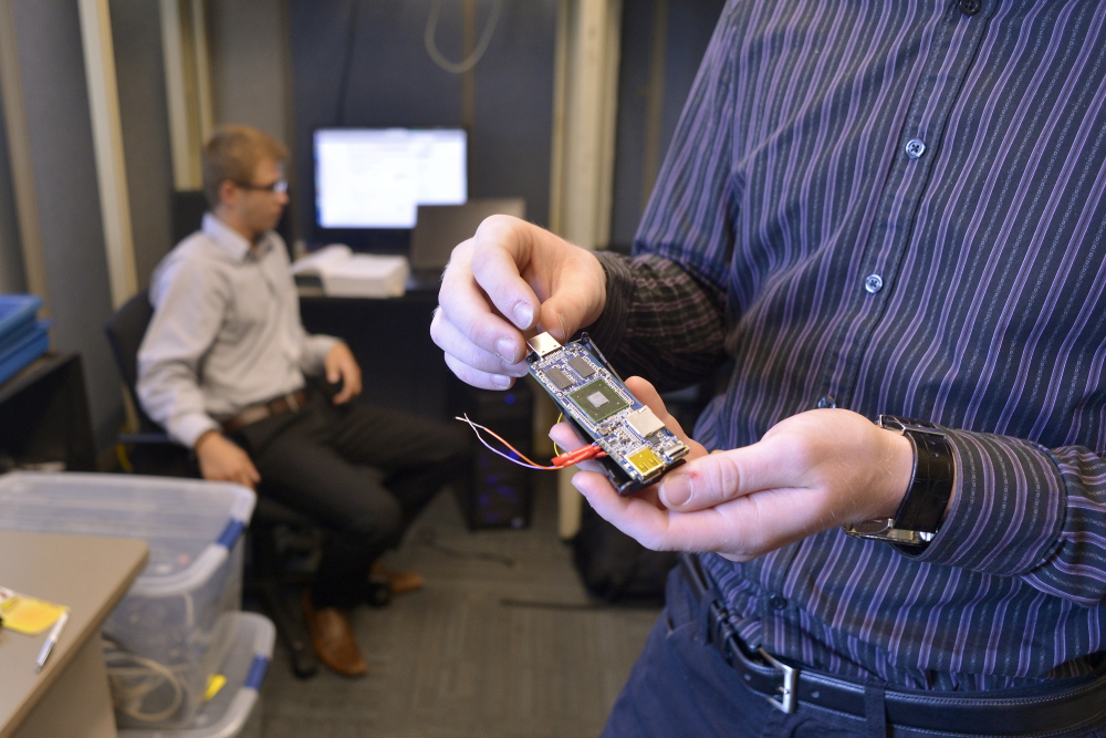 Samuel Barton, right, and Michael Guesev display a microcomputer Wednesday at the University of Southern Maine’s new cybersecurity laboratory in Portland. The microcomputer is designed to set up a network of sensors for data monitoring for security purposes.
