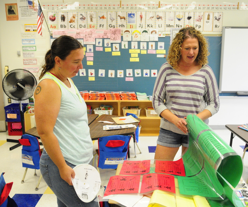 First grade teachers Shannon Morgan, left, and Jessica DeJongh look at the riddles Morgan had printed out for her students as they ready their classrooms at Farrington Elementary in Augusta for the new school year on Friday