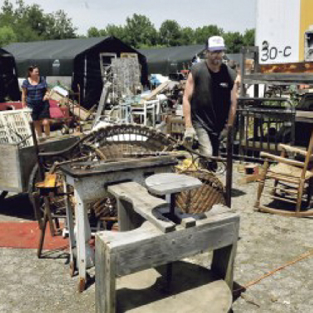 Robert Dale, owner of Maine 201 Antiques in Fairfield, walks around piles of scattered merchandise at his Fairfield property in June.