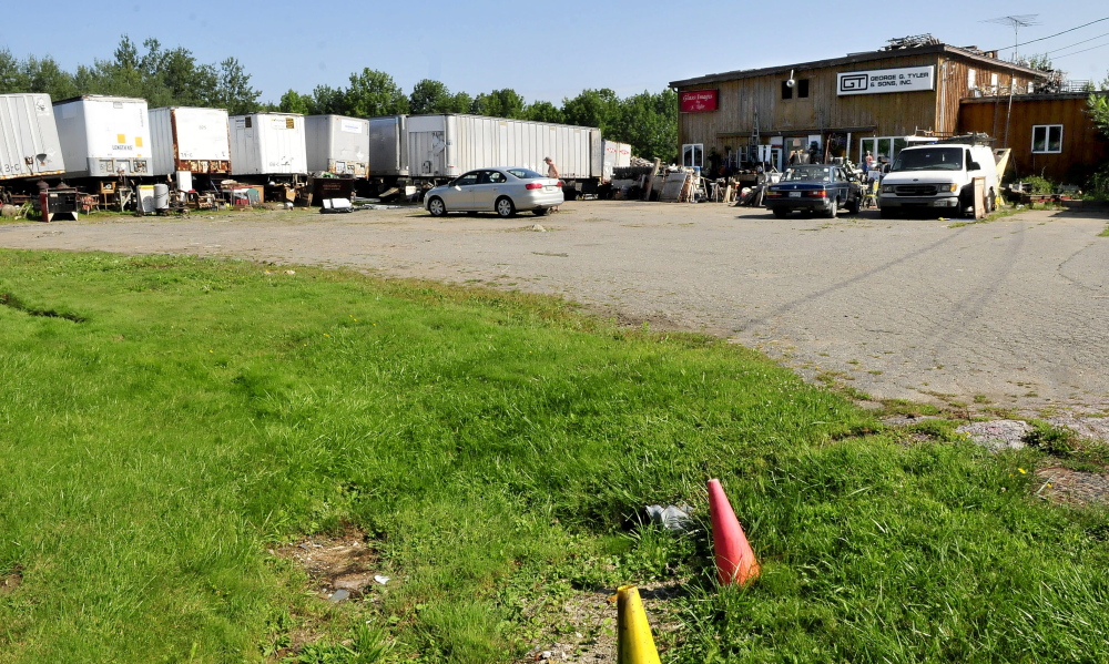 A man steps out of a car at the Maine 201 Antiques business in Fairfield on Sunday. The area in foreground was recently filled with used household and building materials which have been consolidated inside and behind trailers in background.