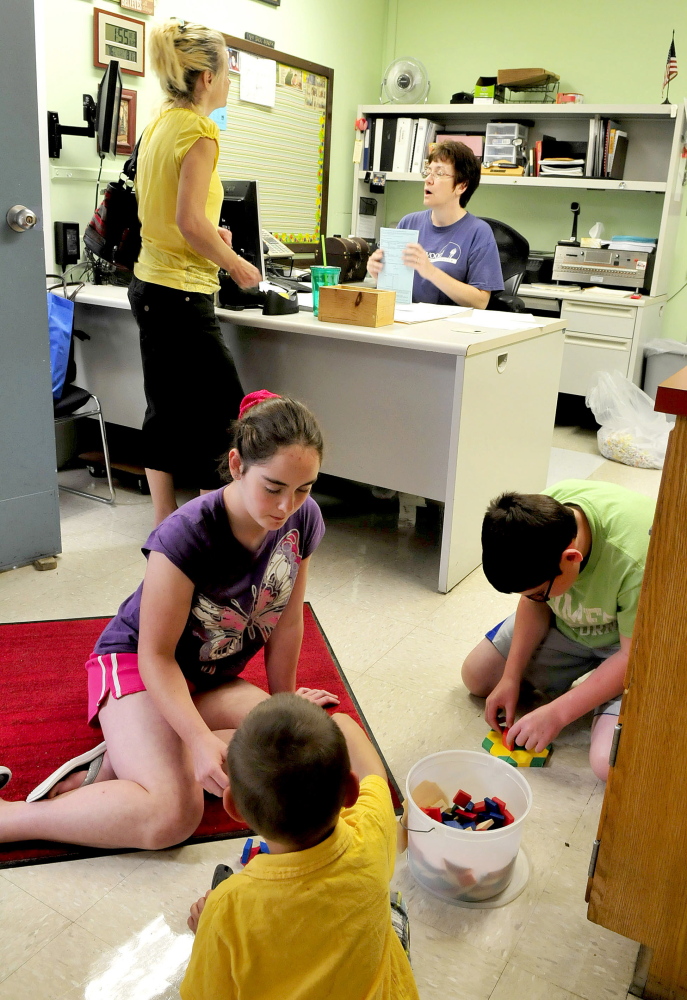 Athens Community School secretary Nancy Martin, seated, speaks with Karen Lancaster as children Jayce Rose, front, and Lucy and Luke Perkins play a game in the front office.