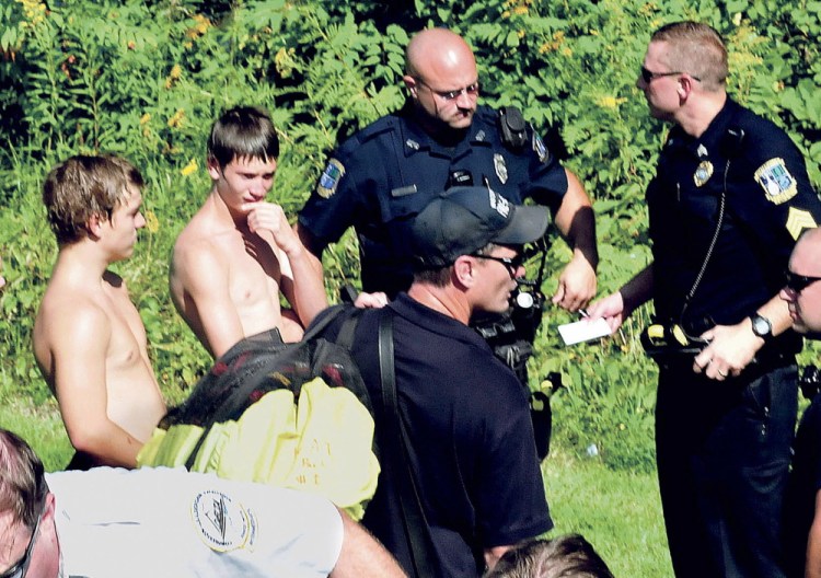 Police and rescue personnel speak with Aerrin Landry, 15, of Clinton, left, and Parish Napoleone, 14, of Winslow, who saw a woman jump from the Two-Cent Bridge into the Kennebec River and who jumped into the river and tried unsuccessfully to rescue her.