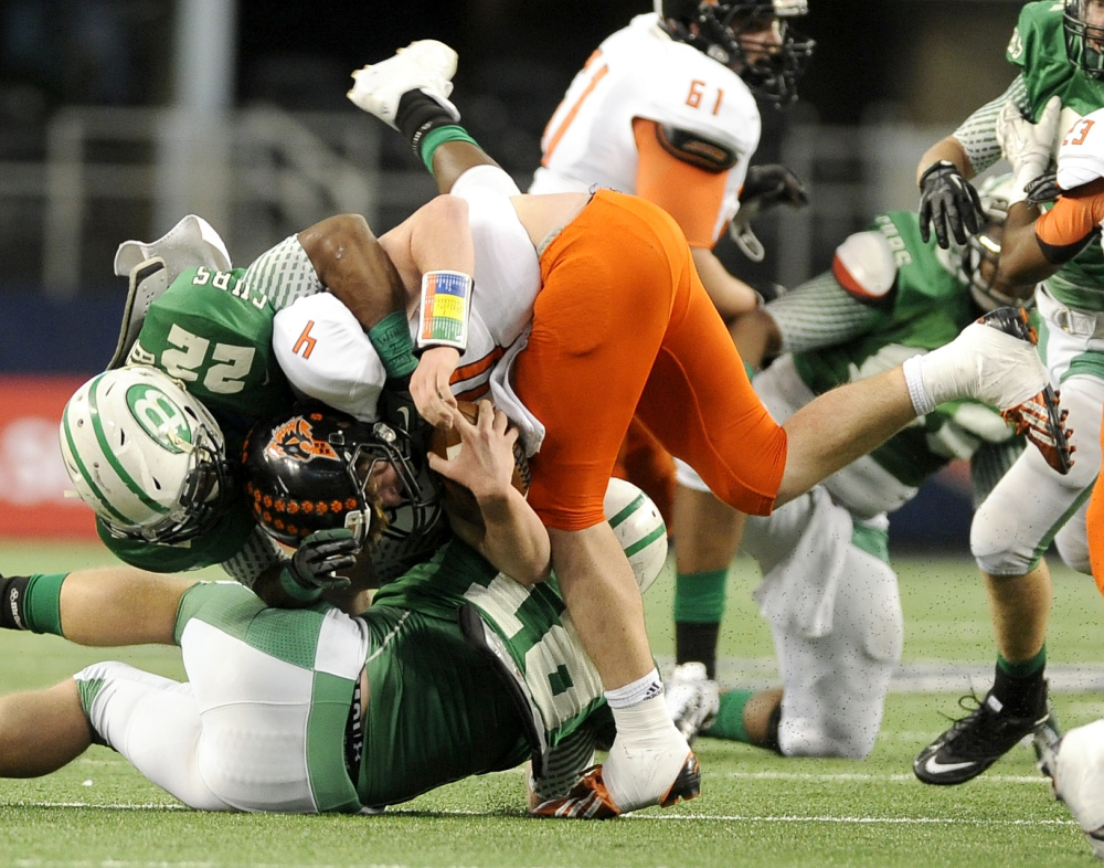 In this Dec. 2013 photo, Aledo quarterback Luke Bishop (4) is tackled by Brenham’s Ryan Nunn (22) in the first half during the UIL Class 4A, Division II high school football championship game in Arlington, Texas. Nearly half of parents say they’re not comfortable letting their child play football amid growing uncertainty about the long-term impact of concussions, according to an Associated Press-GfK poll. A majority, however, say they haven’t prevented their child from playing the game they love.