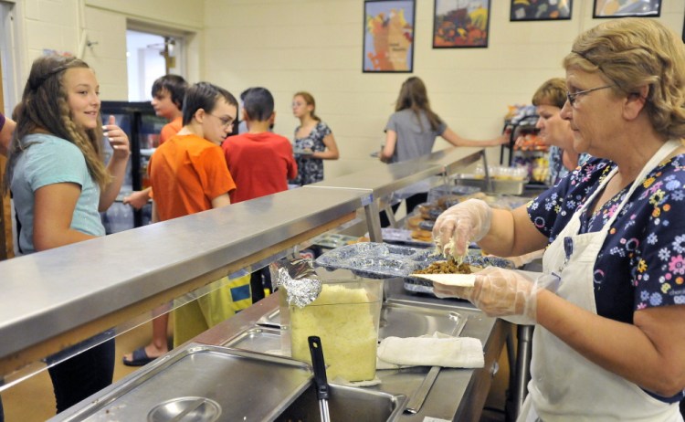 Layna LaBranche, right, serves tacos to students Friday during lunch period at Waterville Junior High School.