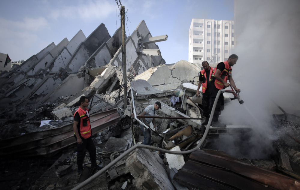 In this Aug. 26, file photo, Palestinian firefighters extinguish a fire in the rubble of the destroyed 15-story Basha Tower, following early morning Israeli airstrikes in Gaza City.