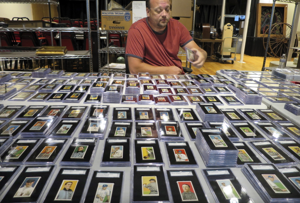 Troy Thibodeau, from Saco River Auction Co., examines a collection of more than 1,400 baseball cards from 1909, 1910, and 1911 in Biddeford. The collection will be auctioned off starting in January 2015.
