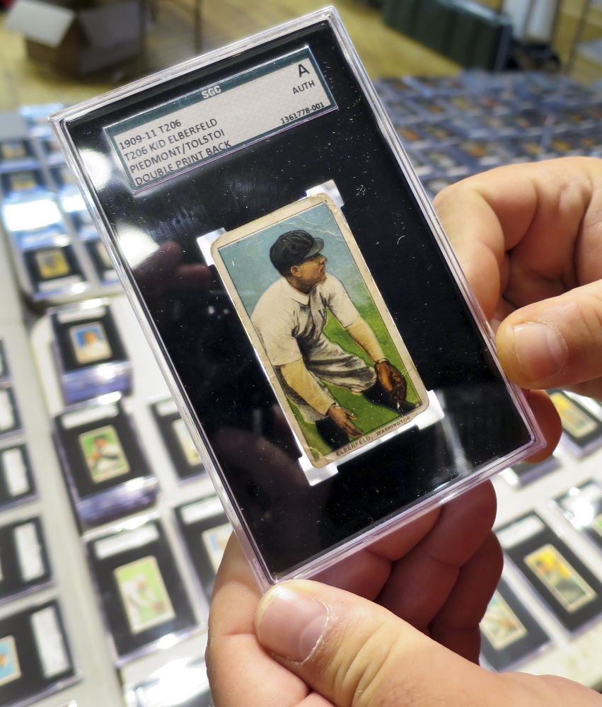 A 1909 baseball card depicting Kid Elberfeld is held by Troy Thibodeau at Saco River Auction Co., in Biddeford.