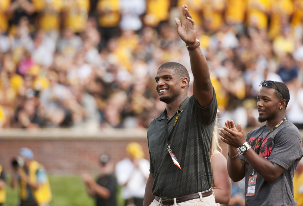 Former Missouri player Michael Sam, left, waves to fans has he and former teammate E.J. Gaines, right, are introduced during the first quarter of the South Dakota State-Missouri NCAA college football game Saturday, in Columbia, Mo.