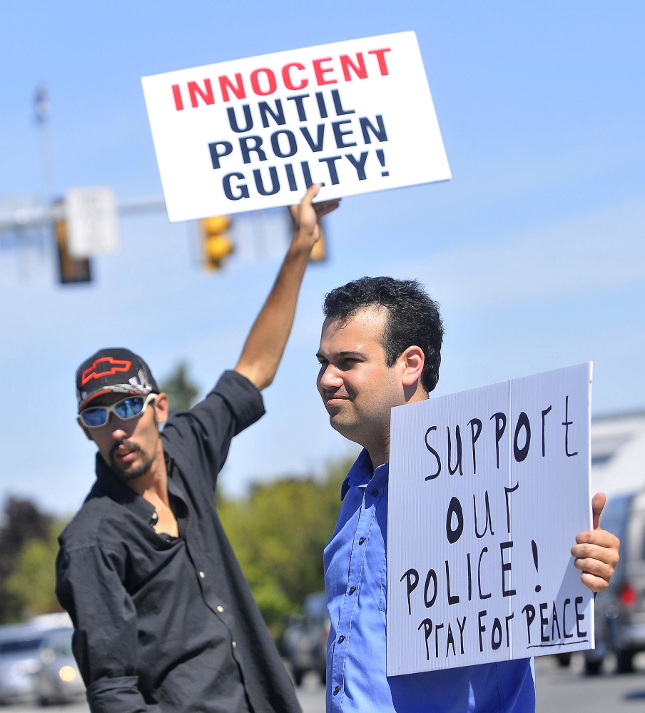 Jibryne Karter III, right, and Christopher Gruhn, back left, hold up signs Thursday on the corner of Main and Elm streets in Waterville in support of Officer Darren Wilson, who shot and killed Michael Brown last month in Ferguson, Mo.