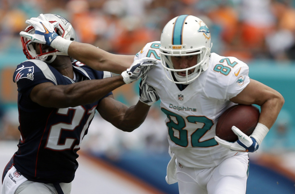 Dolphins wide receiver Brian Hartline defends against a tackle by Patriots cornerback Malcolm Butler in Sunday’s game at Miami Gardens, Fla.