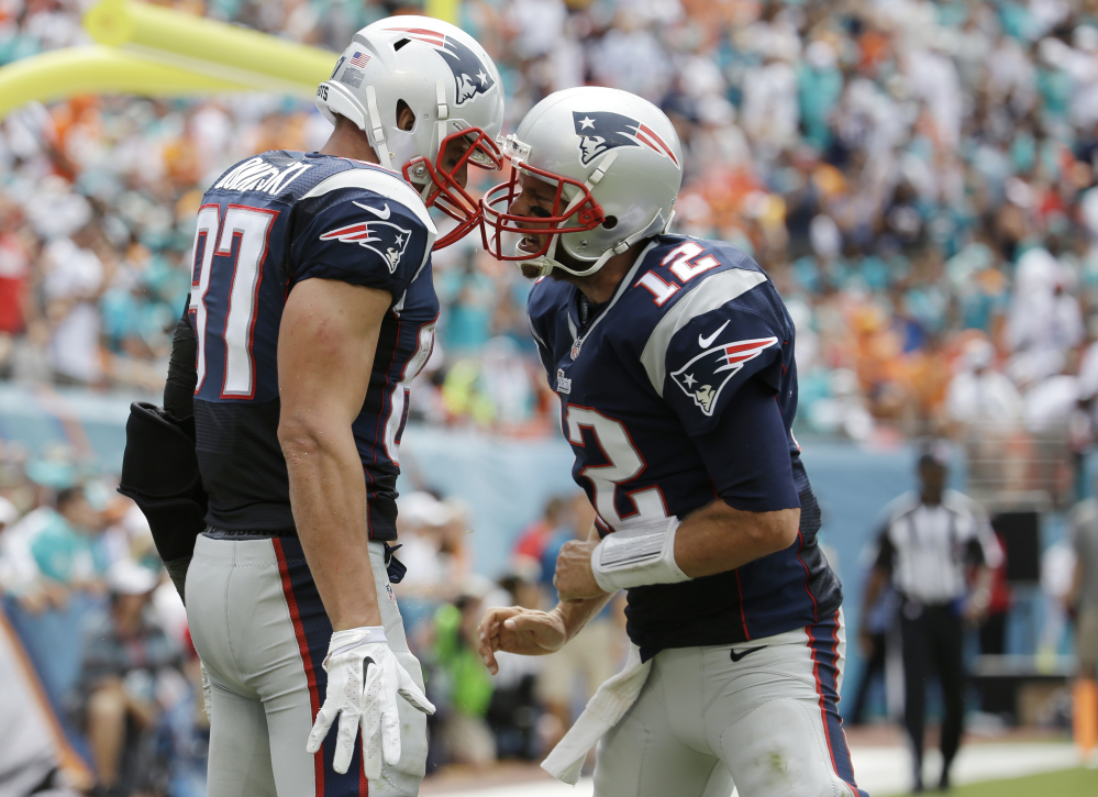 Patriots quarterback Tom Brady, 12, celebrates a touchdown with tight end Rob Gronkowski in the second quarter of Sunday’s game at Miami Gardens, Fla.