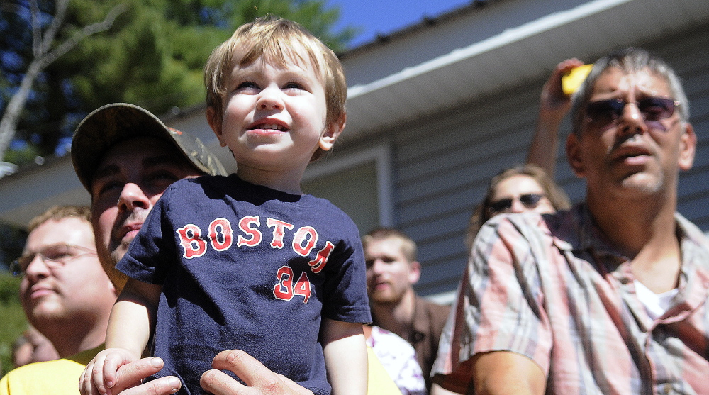 Zackary Hafner, 1, in the arms of his father, Miles, watches the demolition derby held at the Litchfield Fair on Sunday.