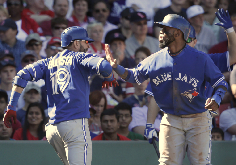 Toronto’s Jose Bautista, left, is welcomed at home by Jose Reyes, right, after hitting a three-run home run off a pitch by Boston’s Rubby De La Rosa in the fifth inning Sunday at Boston.