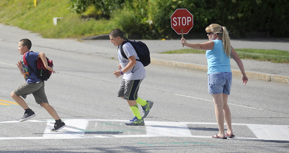 Former crossing guard Sherry McArthur escorts children across Western Avenue in Augusta during the first week of school. McArthur has volunteered to help cross this school year. The city eliminated paid crossing guards over the summer.