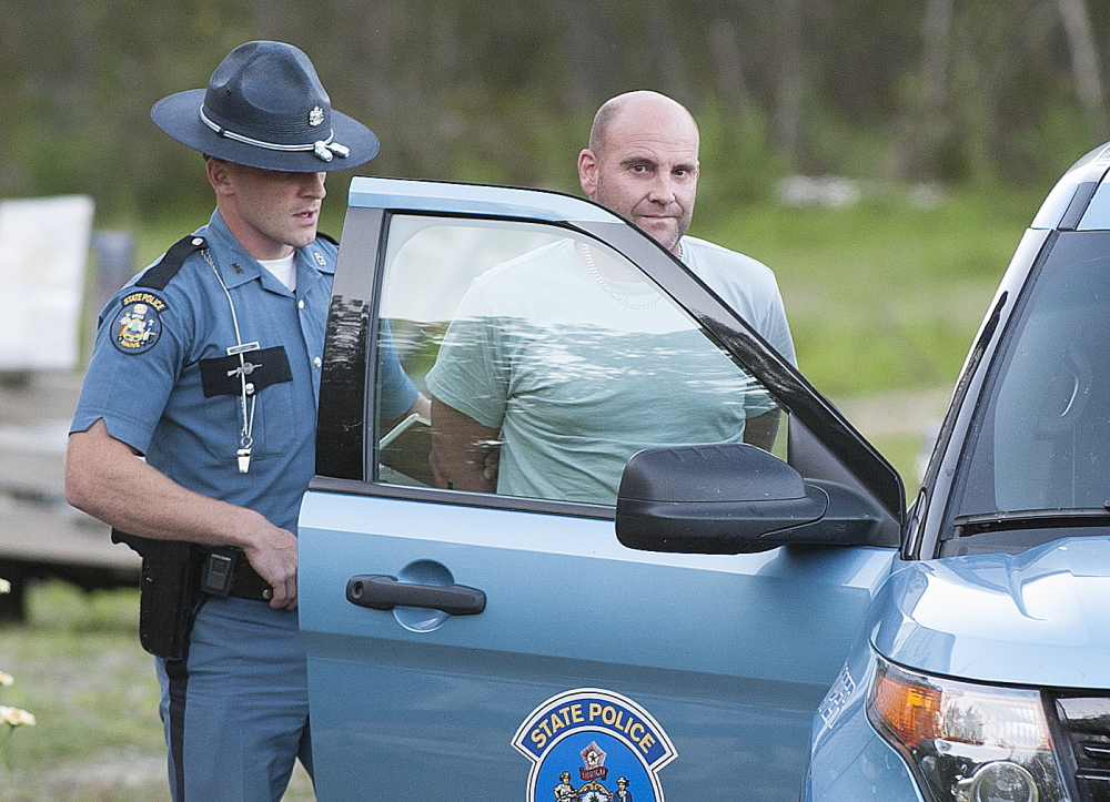 Maine State Police Trooper Scott Duff leads Marc Alberi of Newport to his cruiser in handcuffs after serving him with a search warrant on Monday.