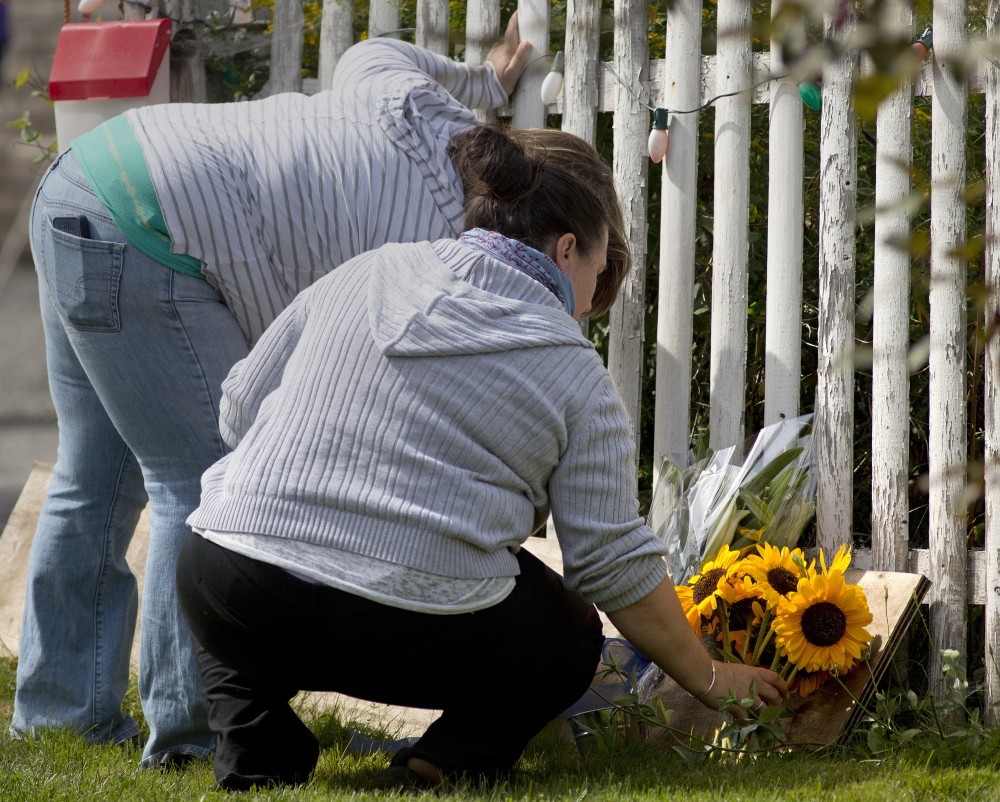 Two women lay flowers Tuesday outside the home of James Laurita. Many residents in the close-knit community of about 1,500 found it difficult to talk about his death.