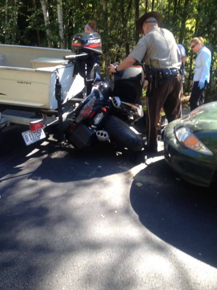 A deputy sheriff examines the wreckage after a motorcycle was sandwiched between a sedan and a boat being towed by a pickup truck Tuesday afternoon on U.S. Route 2 in Canaan. Three people were taken for hospital treatment, with the motorcycle driver being the most seriously injured.