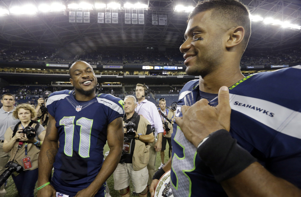Seattle Seahawks’ Percy Harvin (11) and Russell Wilson smile after the team defeated the Green Bay Packers 36-16 in an NFL football game, Sept. 4, in Seattle.