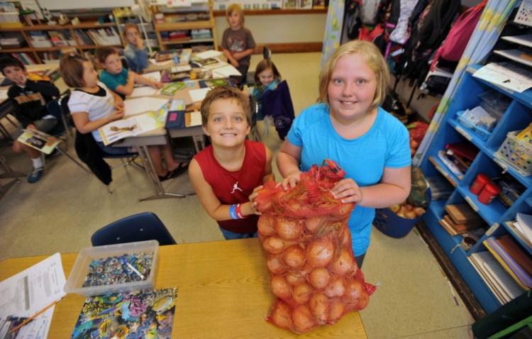Albert S. Hall fifth-graders Jacob Luff, 11, left, and Eleanor King, 10, stand with a sack of donated onions at the school in Waterville on Wednesday.