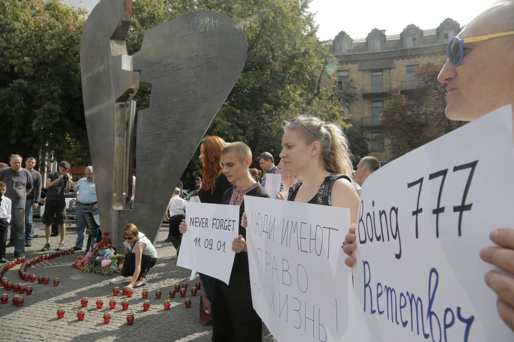 Ukrainians hold posters during a remembrance ceremony in memory of the Sept. 11 terror attacks  in the United States and memory of the people, who died during the Boeing 777, Malaysia Airlines flight MH17 crash in eastern Ukraine at the monument of victims of terror in Kiev.