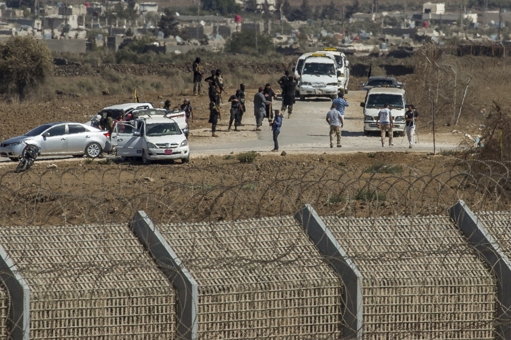 Al-Qaida-linked Syrian militants gather around vehicles carrying U.N. peacekeepers from Fiji before releasing them, as they arrive near the Syrian village of Al Rafeed in Syrian-controlled side of the Golan Heights on Thursday.