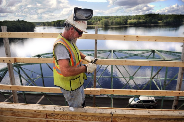 Reed & Reed Inc. worker Bob St. Pierre clips a piece of wire Wednesday to secure reinforcing steel on the deck of the new bridge the firm is constructing over the Kennebec River between Richmond and Dresden. Tom Reed, who is overseeing the project for the Woolwich company, said he hopes to have the bridge open by Thanksgiving. Crews will then begin to disassemble the old swing bridge below.
