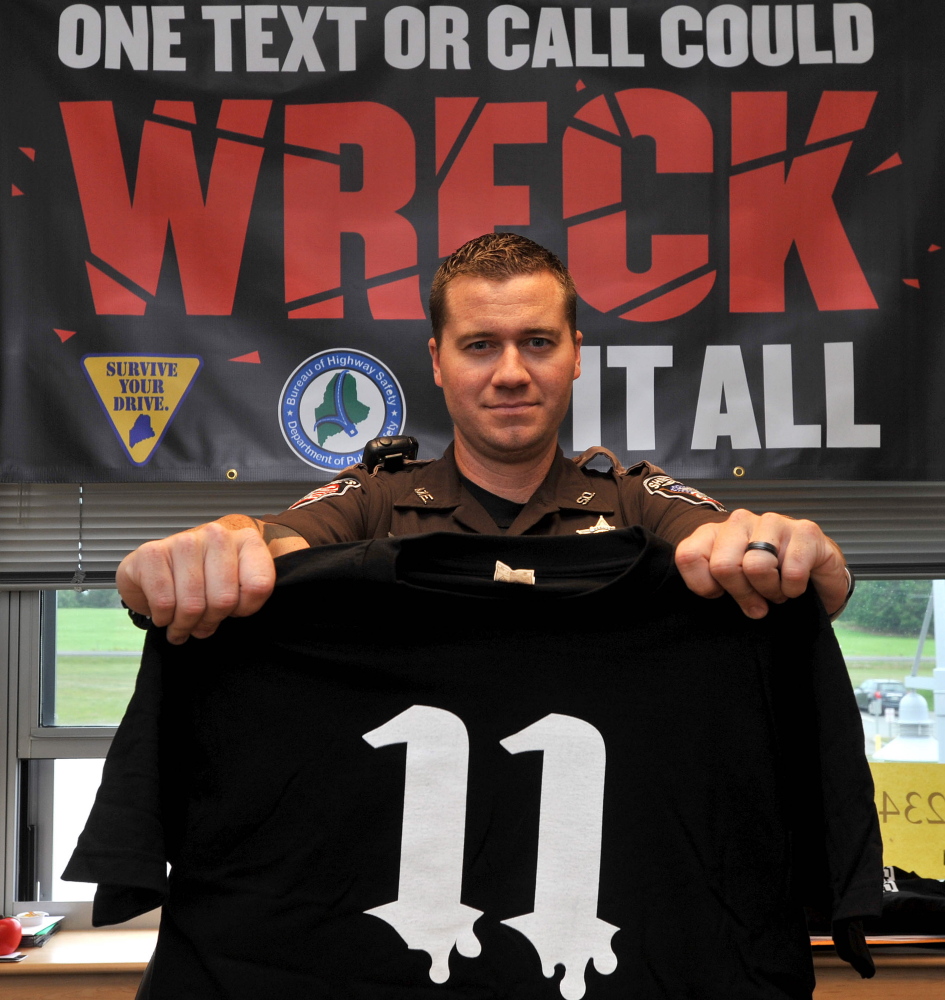 Deputy Nick Oettinger, of the Waldo County Sheriff’s Office, the school resource officer at the Mount View School in Thorndike, holds up a T-shirt promoting safe driving Thursday. The anti-texting initiative Project 11 T-shirts display the number 11 to indicate that 11 people will die each day in accidents caused by people texting while driving.