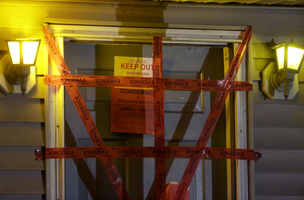 A “condemned” sign is attached behind police tape to the front door of a house where a Massachusetts prosecutor said the bodies of three infants were found.