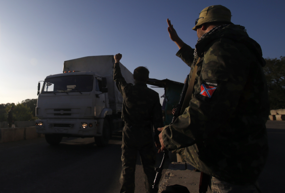 Pro-Russian rebels wave to trucks marked as Russian aid convoy to Ukraine as they return to Russia near the town of Krasnodon, eastern Ukraine, Saturday.
