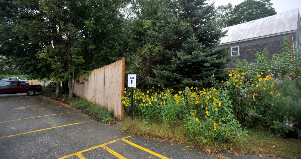 A newly erected 9-foot-high fence separates the New Balance factory from the Ames residence on Depot Road in Norridgewock.