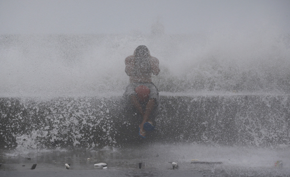 A Filipino reacts as he is hit by waves along a promenade in Manila, Philippines, on Sunday.