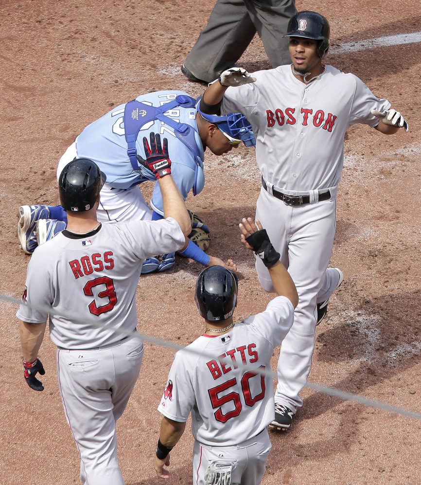 Boston Red Sox’s Xander Bogaerts, right, is welcomed home by David Ross (3) and Mookie Betts (50) after hitting a three-run home run during the third inning of a baseball game against the Kansas City Royals Sunday.